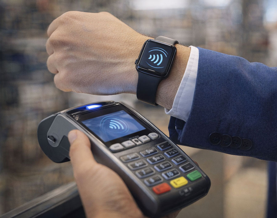 Zahlvorgang mit Uhr wird gezeigt. Uhr an Handgelenk wird an das Kartenlesegerät gehalten und das Übertragungssymbol gezeigt.